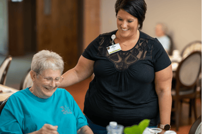 Staff member assisting a smiling resident at a table