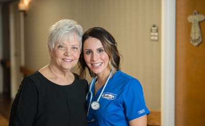 Staff member with resident smiling in the hallway
