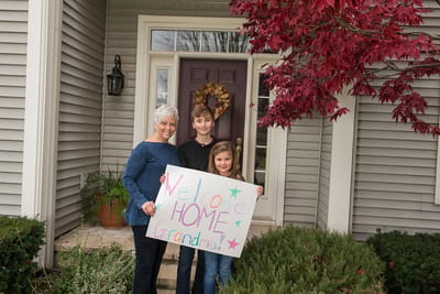A family welcomes their grandmother home with a sign