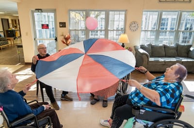 Residents playing with a colorful parachute in a common area