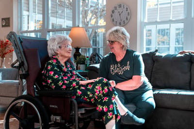 A resident and staff member in a cozy living area