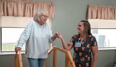 A resident and staff member smiling and interacting indoors