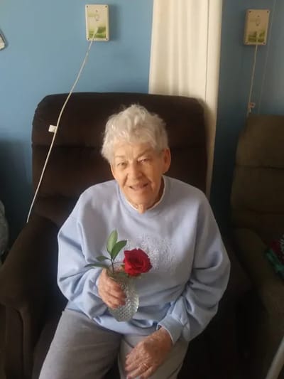 Elderly resident holding a rose in a chair