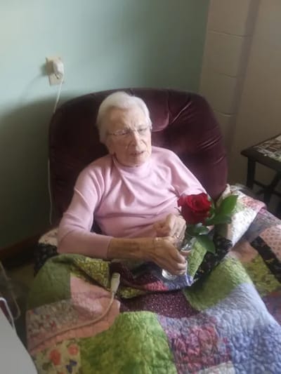 Senior woman holding a rose in her room