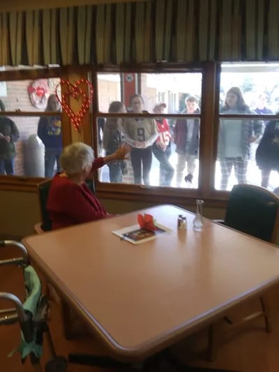 Residents interacting through a dining room window