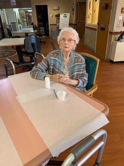 Elderly resident sitting at a table in a common area