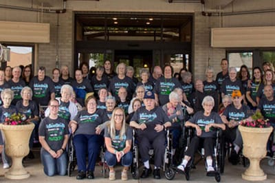 Residents and staff posing outside the facility entrance