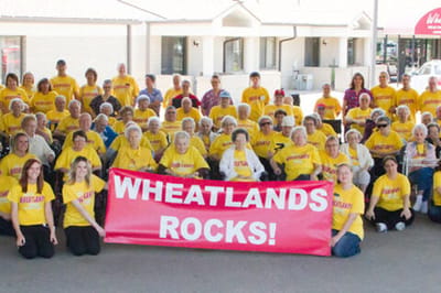 Group of residents celebrating with a banner at the facility