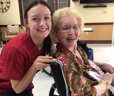A staff member smiling with a resident in a hallway