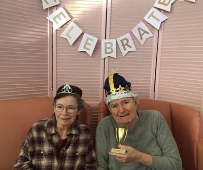 Residents celebrating in festive hats with a trophy