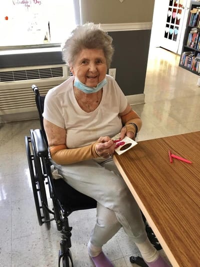 A resident crafting at a table in an activity room
