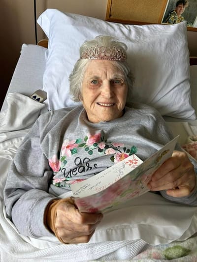 Senior resident reading a card in bed