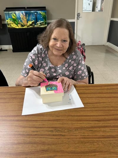 Resident engaged in an art activity with a painted box