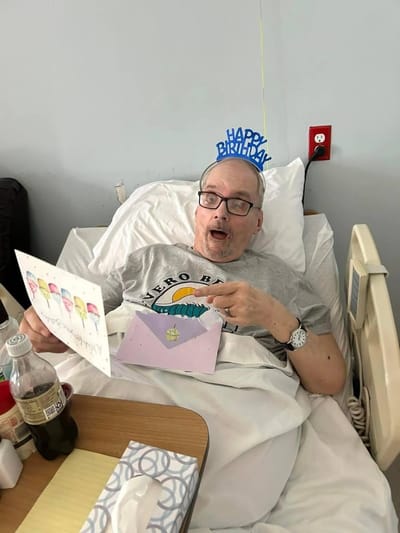 Resident celebrating birthday in bed with cards