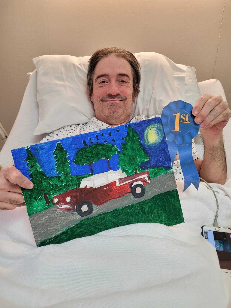 Resident celebrating art competition win with painting and ribbon