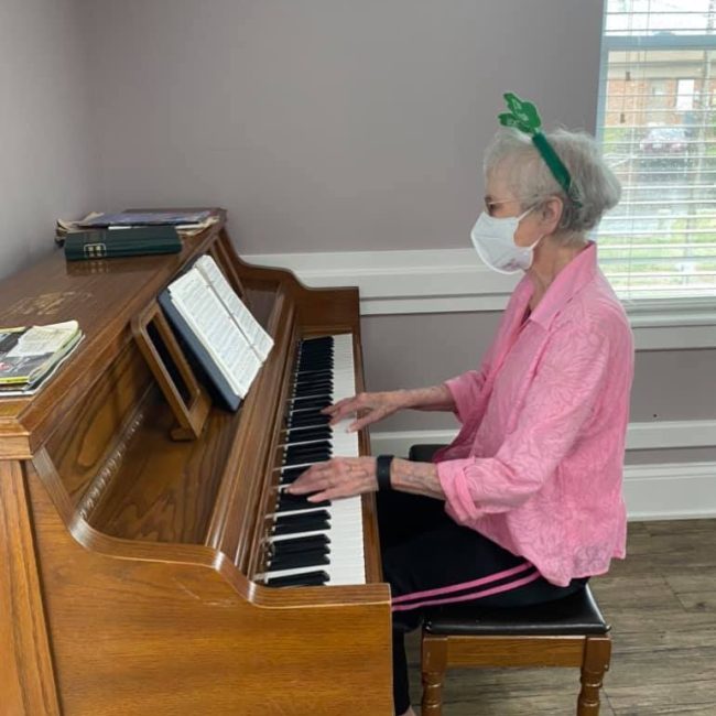Resident playing piano in a cozy interior setting