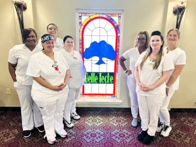 Staff members posing near a colorful stained glass window
