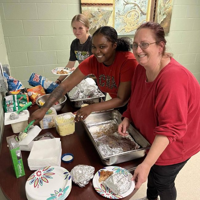 Staff and residents serving food in a dining area