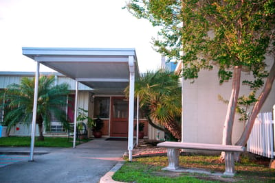 Entrance of a senior living facility with palm trees
