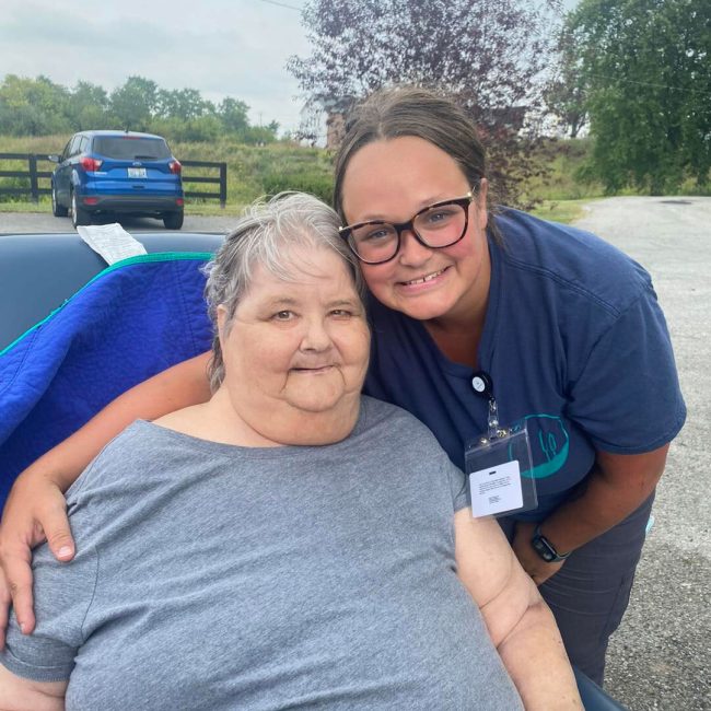 A resident and staff member smiling outdoors