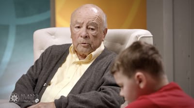 An elderly man listening to a young boy