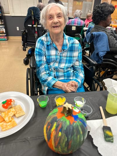Resident painting a pumpkin at a group activity