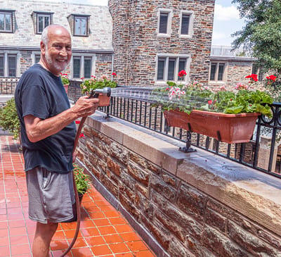 Resident watering flowers on a sunny outdoor terrace