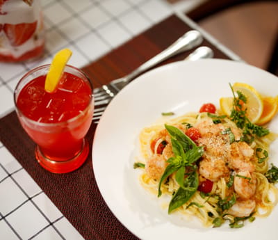 Plate of shrimp pasta and a drink on a table