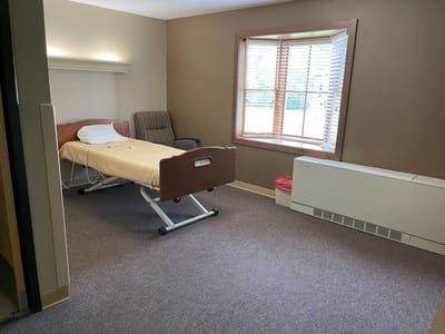 A private resident room with a hospital bed and chair