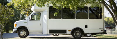 Facility transport vehicle parked under trees