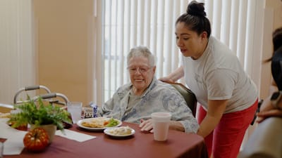 Resident enjoying a meal with staff assistance