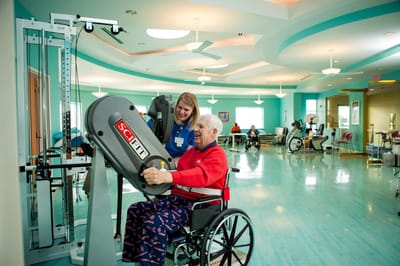 Resident participating in exercise with staff assistance