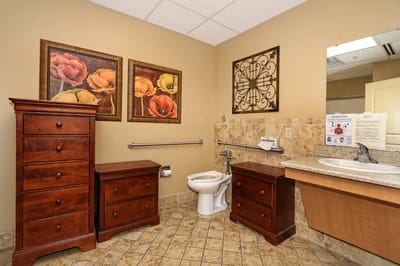 Clean bathroom with wooden cabinets and floral artwork