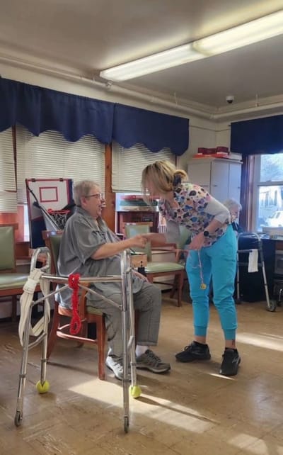 A staff member assisting a resident in an activity room
