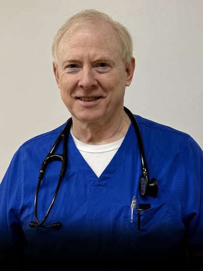 A healthcare professional in blue scrubs smiling