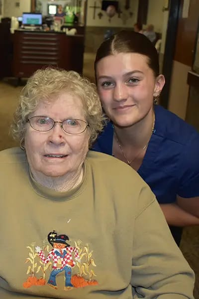 A resident smiling with a staff member in a cozy setting