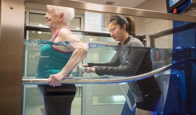 Senior resident in therapy with staff assistance in water