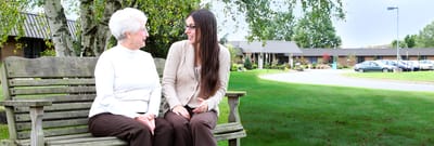 Two residents sitting on a bench in a garden