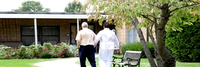 Two individuals walking in a garden area