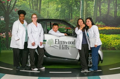 Staff members posing with a facility vehicle in an indoor setting