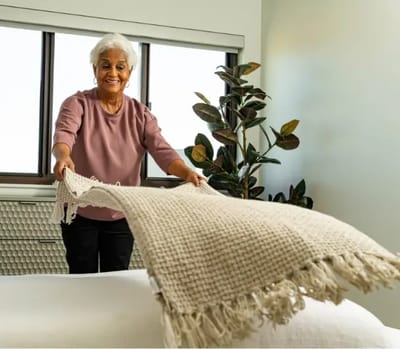 A resident folding a blanket in a bright room