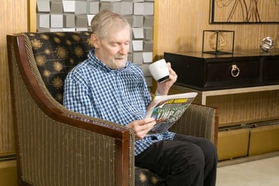 Senior man reading a newspaper in a cozy chair