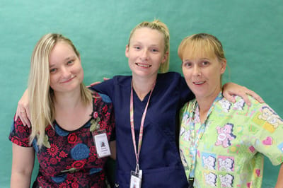 Three staff members posing with smiles