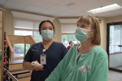 Healthcare staff assisting a resident in an activity room