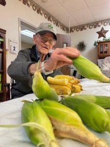 Midwest Covenant Home, Nursing Home in Stromsburg, NE — Senior resident preparing corn in a communal activity space
