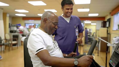 Resident exercising with staff support in a activity room