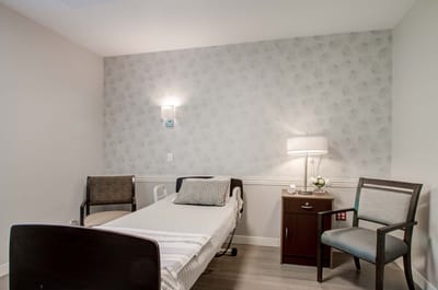 Bright and cozy resident room with bed and chairs