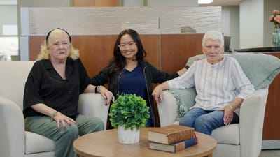 Two residents and a staff member in a cozy lounge area
