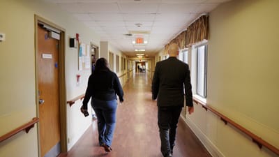 Two residents walking down a brightly lit hallway