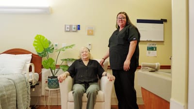 A staff member assists a resident in their room